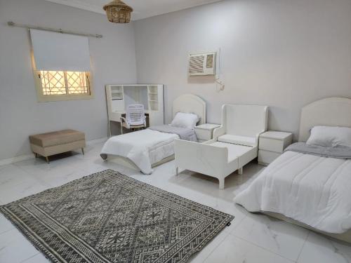 a white bedroom with white furniture and a rug at شقة عائلية فخمة in Al Madinah