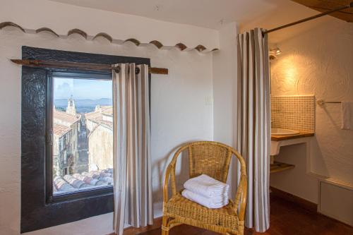 Cette chambre dispose d'une chaise et d'une fenêtre avec vue. dans l'établissement Hôtel Restaurant Les Remparts, à Venasque