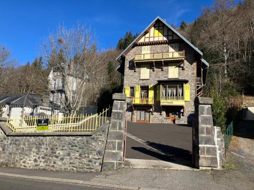 a house with a yellow gate in front of it at Le Mont Dore Résidence Cottage rez de chausse in Le Mont-Dore