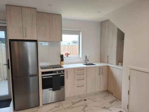 a kitchen with wooden cabinets and a stainless steel refrigerator at Stylish Townhouse in City Centre in Christchurch