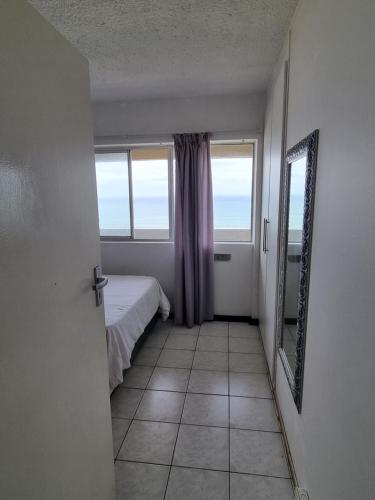 a room with a bed and a mirror and a window at Stella Maris 117 Amanzimtoti in Amanzimtoti