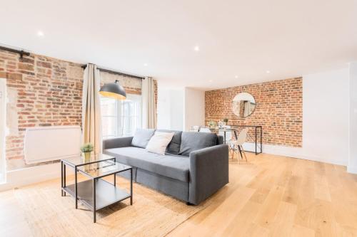 un salon avec un canapé et un mur de briques dans l'établissement Old Lille - Lovely typical apartment!, à Lille