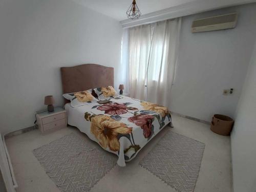 um quarto com uma cama com um edredão floral em Appartement Cozy aux Berges du Lac 1 em Tunes