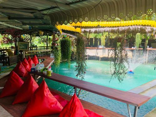 a swimming pool with red pillows and a bench in front at Kanda Hill Resort in Ban Na Sok