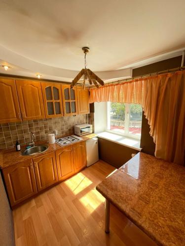 a kitchen with wooden cabinets and a sink and a window at Изумруд in Petropavlovsk