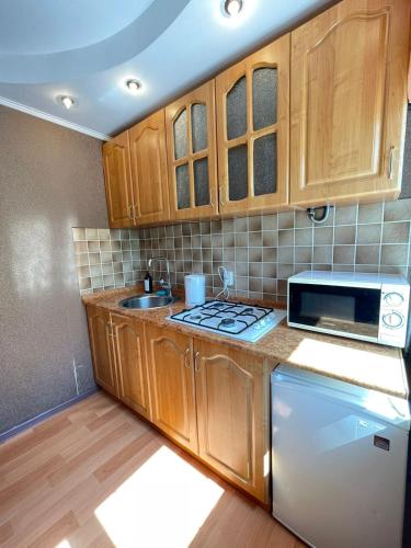 a kitchen with wooden cabinets and a sink and a microwave at Изумруд in Petropavlovsk