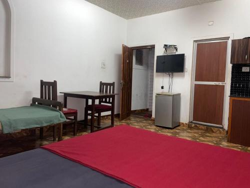 ein Wohnzimmer mit einem Tisch und einem roten Teppich in der Unterkunft Pihuu hotel in Calangute