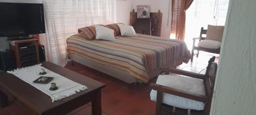 1 dormitorio con 1 cama, TV y sillas en Habitación Gabriela Mistral, en Colonia del Sacramento