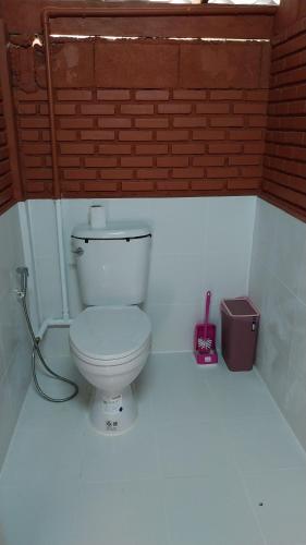 a bathroom with a toilet and a brick wall at Eden Farmstay CNX 