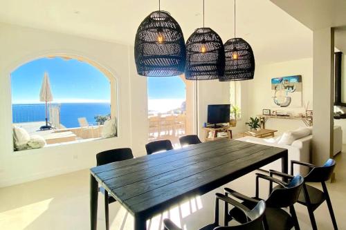 une salle à manger avec une table et des chaises avec vue sur l'océan dans l'établissement maison vue mer panoramique et jacuzzi, à Théoule-sur-Mer