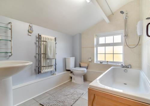 a bathroom with a toilet and a tub and a sink at Valentine Cottage in Snape