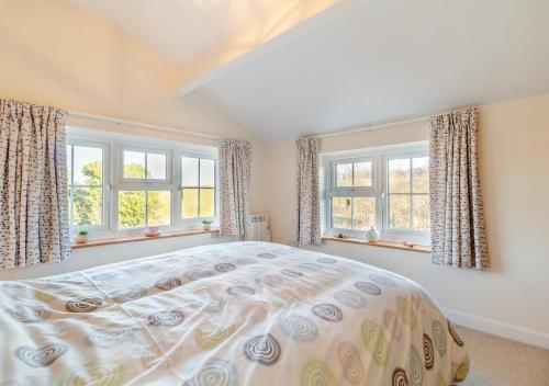 a bedroom with a bed and two windows at Valentine Cottage in Snape