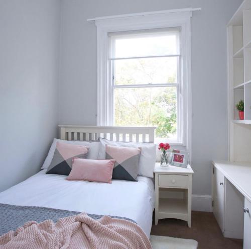 una camera da letto con un letto bianco con cuscini rosa e grigi di Beautiful 2-Bed Apartment in London a Londra