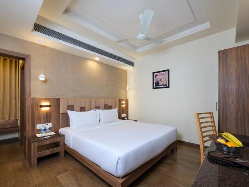 a bedroom with a large white bed and a desk at Pride Biznotel Sasan Gir in Sasan Gir