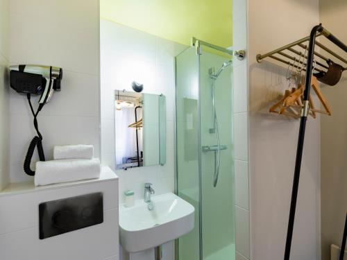 a bathroom with a sink and a glass shower at MOKA Hôtel in Lorient