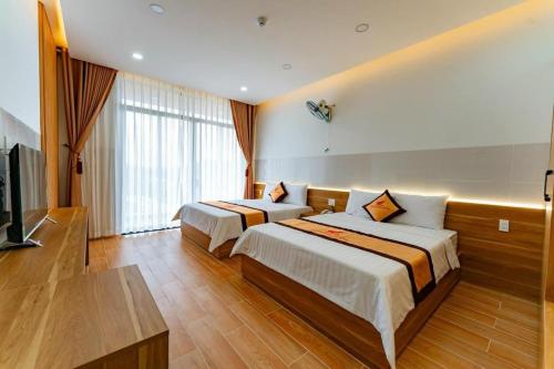 KHÁCH SẠN HÀ PHƯƠNG في Tánh Linh: غرفة فندقية بسريرين وتلفزيون بشاشة مسطحة