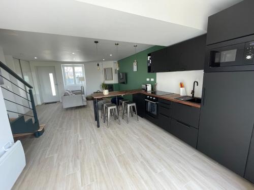 eine Küche mit schwarzen Schränken und Holzböden in der Unterkunft Maison avec vue imprenable sur la Brière in Saint-Joachim
