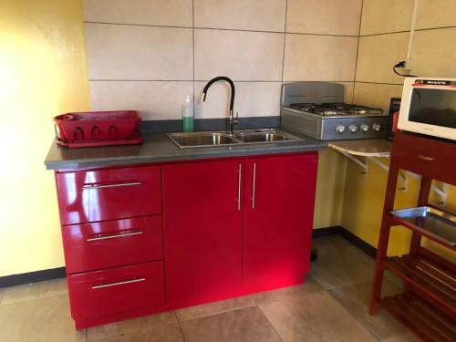 - une cuisine avec des placards rouges et un évier dans l'établissement Logerthine Studio Suriname, à Paramaribo