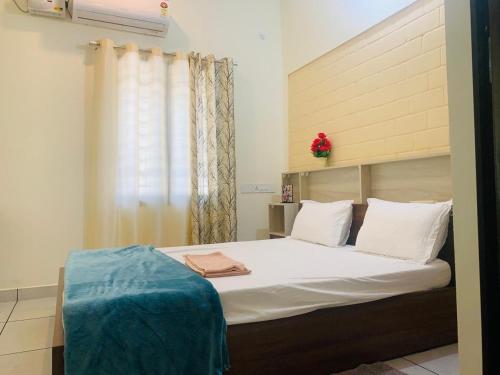 Joann Serviced Apartment في ثيروفالّا: غرفة نوم بسرير وملاءات بيضاء ونافذة