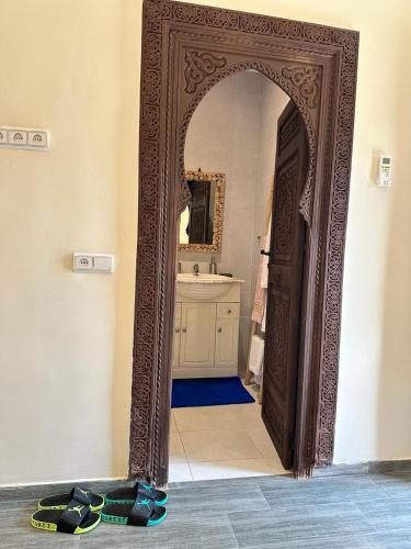 an archway into a bathroom with a sink and a mirror at Oasis Merasi Marrakech in Marrakech