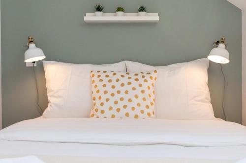 - deux lumières au-dessus d'un lit avec des oreillers blancs dans l'établissement Lille Hypercentre / Gares - Beautiful duplex!, à Lille