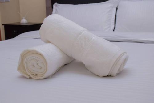 a roll of white towels sitting on a bed at Marvel Homes in Meru