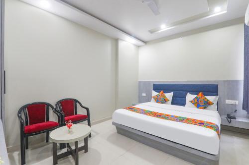 a bedroom with a bed and two chairs and a table at FabExpress Grand Inn I in Lucknow