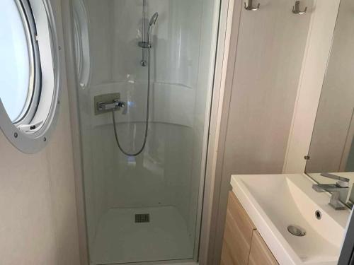 une douche avec une porte vitrée à côté d'un lavabo dans l'établissement Mobil home, à Châteauneuf-de-Galaure