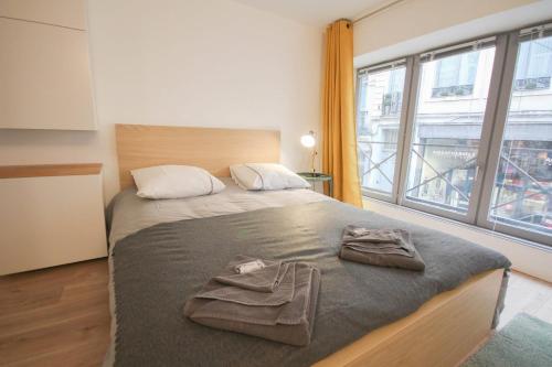 een slaapkamer met een bed en een groot raam bij Lille Grand Place studio center in Lille