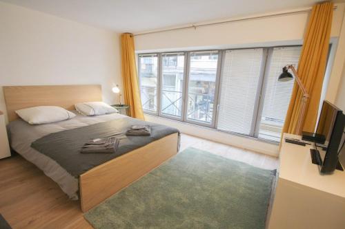 een slaapkamer met een bed en een groot raam bij Lille Grand Place studio center in Lille