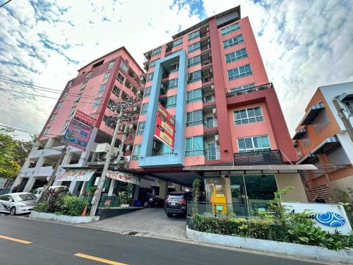 a tall red building with cars parked in front of it at Aryan Suites Hotel in Bangkok