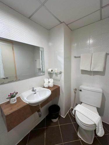 a bathroom with a white toilet and a sink at Aryan Suites Hotel in Bangkok