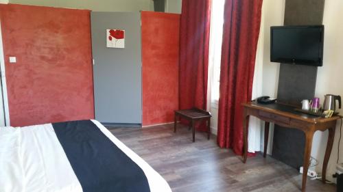 a bedroom with a bed and a desk and a television at Logis Hôtel Restaurant Les Aubuns in Caissargues