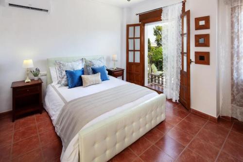 1 dormitorio con 1 cama blanca grande con almohadas azules en TESS Casa La Alcazaba de Serrato, en Serrato