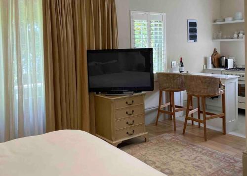 a bedroom with a television on a dresser with a kitchen at The Alphen Cottage in Cape Town