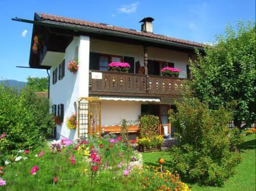 a house with a balcony with flowers in the yard at Ferienwohnung Kramerblick in Grainau