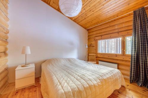 una camera da letto in una baita di tronchi con un letto e una finestra di Holiday Apartment Lomalaavu D 2 a Suomutunturi