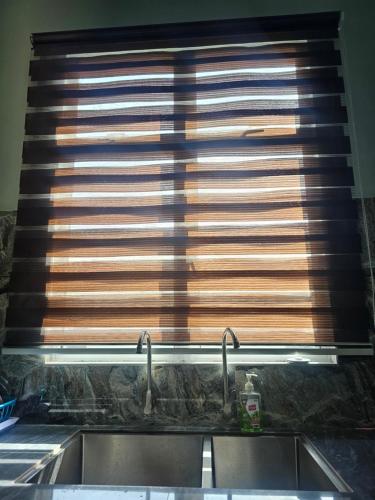 una ventana con persianas de madera sobre un fregadero de cocina en Homestay D'Bunohan, en Tumpat