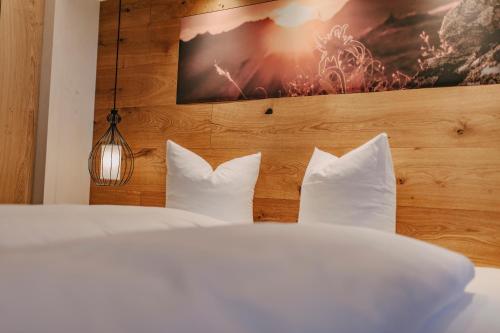 una camera da letto con letto, lenzuola e cuscini bianchi di loisi's Boutiquehotel ad Achenkirch