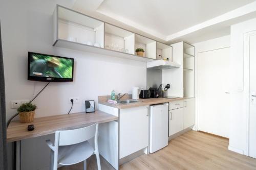 Il comprend une cuisine avec un bureau et une télévision murale. dans l'établissement Lille Hypercentre/Railway stations -Nice studio, à Lille