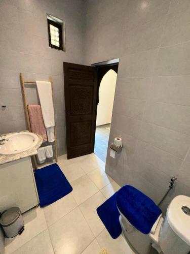 a bathroom with a sink and a toilet with blue mats at Oasis Merasi Marrakech in Marrakech