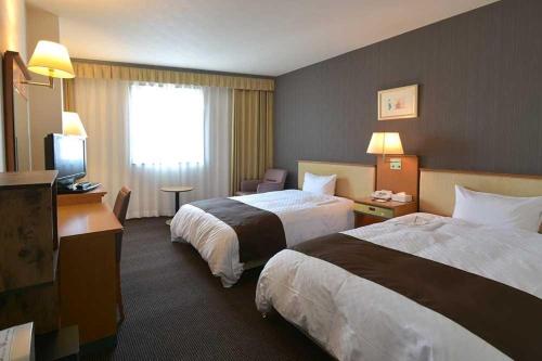 una camera d'albergo con due letti e una televisione di Blossom Hotel Hirosaki a Hirosaki