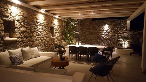 a living room with a couch and a table with chairs at Mykonian Luxury Villa Azure w Sea View and Pool in Agios Stefanos