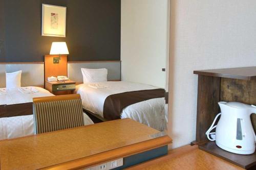 a hotel room with two beds and a desk with a table at Blossom Hotel Hirosaki in Hirosaki