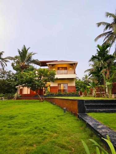 a house with a green lawn in front of it at Savera Seafront in Suratakal