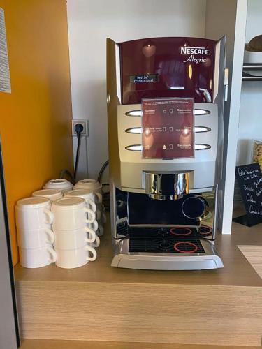 Una cafetera en la parte superior de un estante con tazas en KRYSTAL HOTEL, en Saint-Quentin-Fallavier