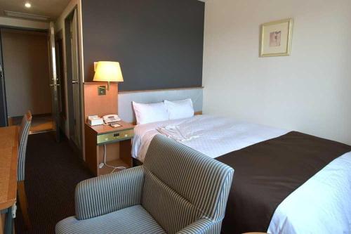 a hotel room with a bed and a chair and a desk at Blossom Hotel Hirosaki in Hirosaki