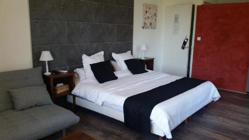 a bedroom with a large bed and a chair at Logis Hôtel Restaurant Les Aubuns in Caissargues