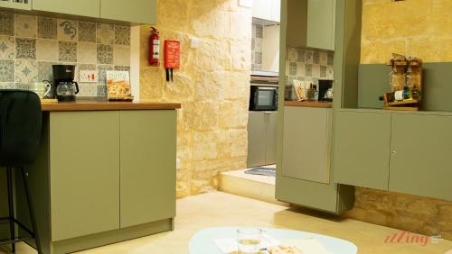 a kitchen with green cabinets and a stone wall at A unique 400-year-old, modern Maltese home in Birgu