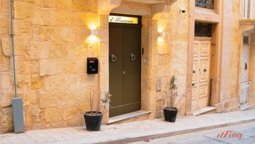 a building with a green door and two potted plants at A unique 400-year-old, modern Maltese home in Birgu